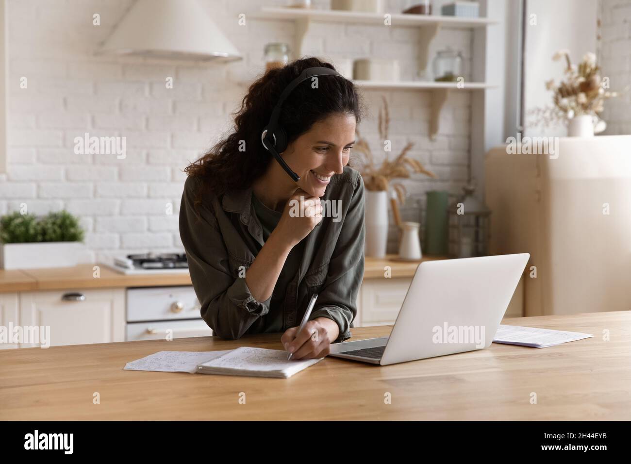 Woman elearning at home listen audio writes notes in copybook Stock Photo