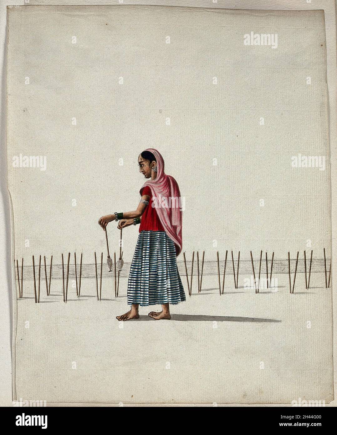 A woman winding thread onto spindles (?). Gouache painting by an Indian artist. Stock Photo