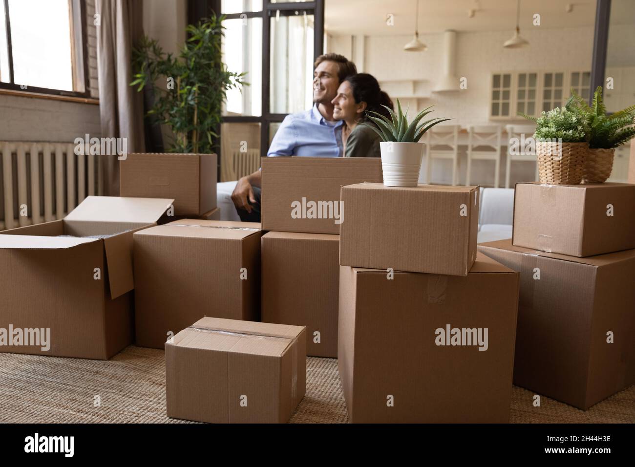 Couple relaxing on sofa near boxes with belongings on relocation Stock Photo
