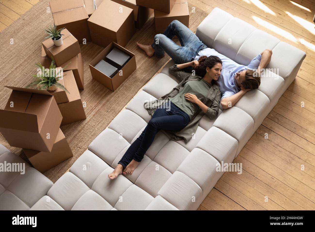 Overhead view couple relaxing on sofa near cardboard boxes Stock Photo
