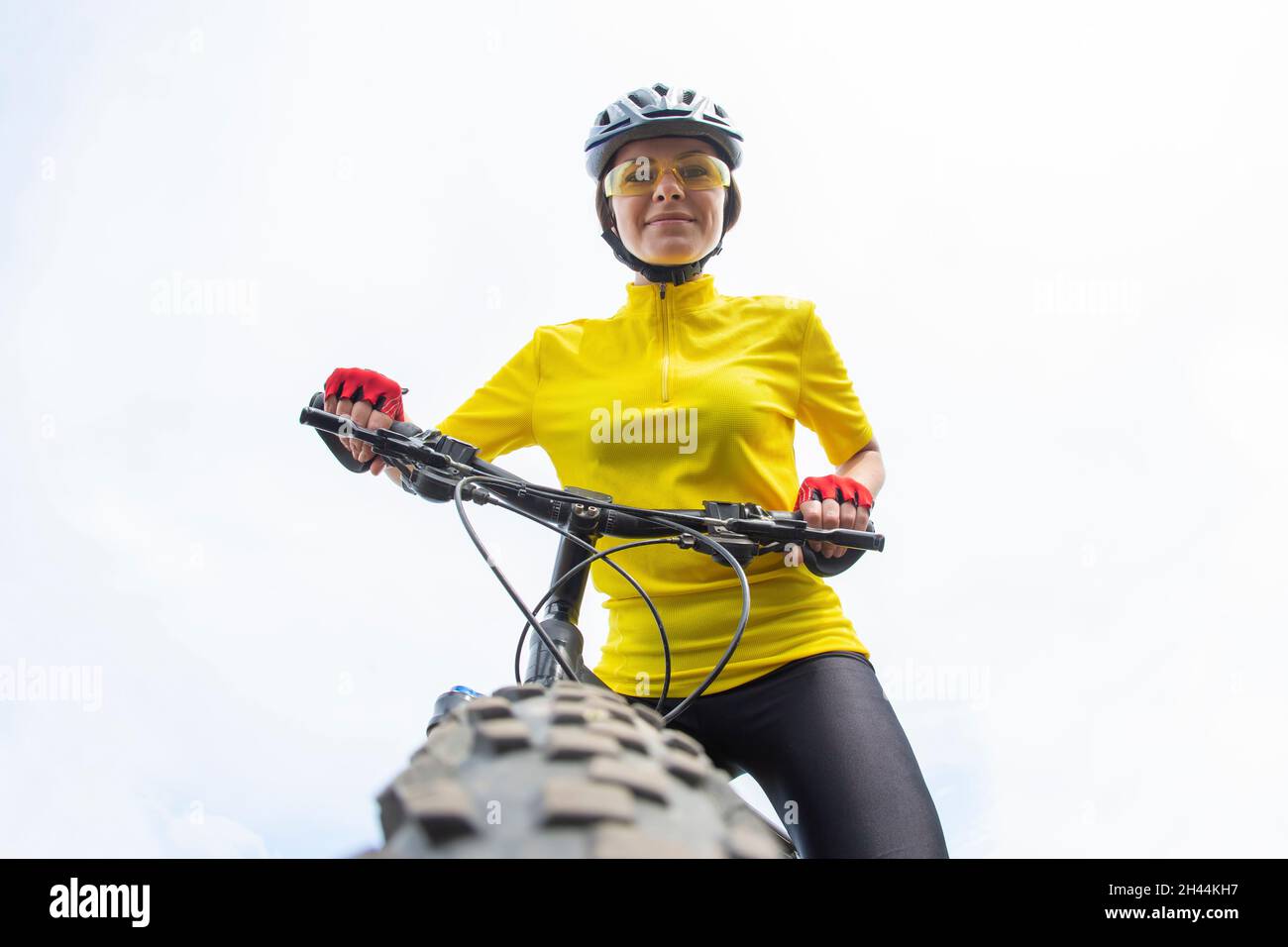 Beautiful woman cyclist looking forward to the wheel of the bike