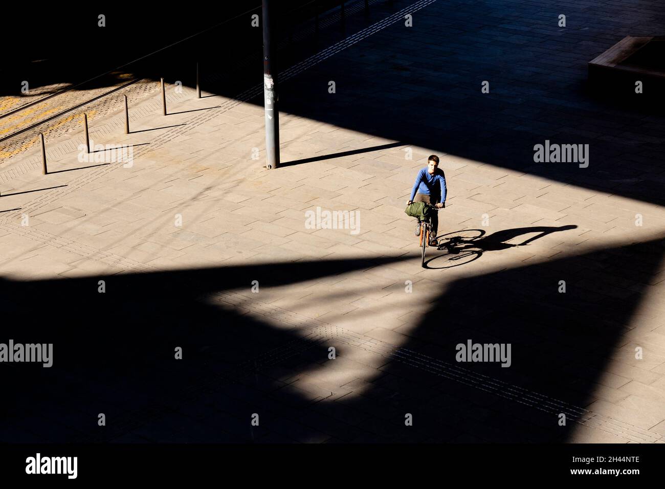 Belgrade, Serbia - October 26, 2020: One teenage boy riding bike on city square in sunlight, high angle view with shadows Stock Photo