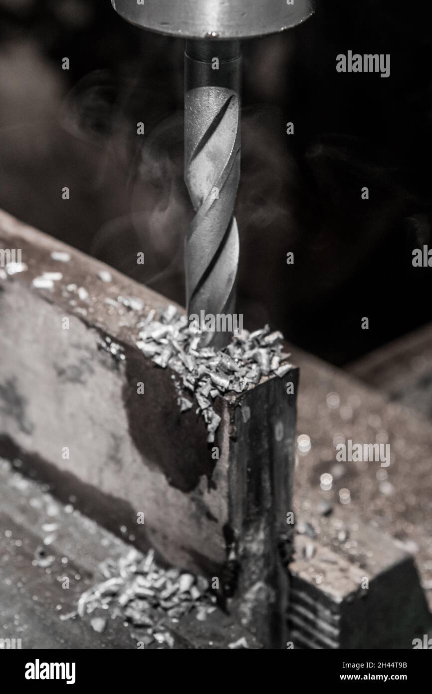 Thick drill drilling old iron bar, steel work equipment closeup Stock
