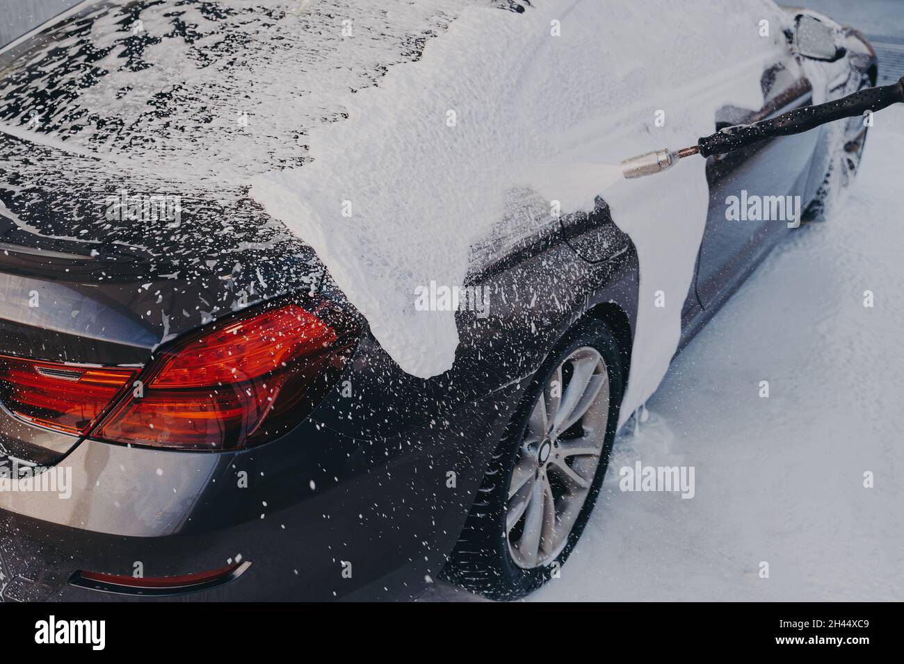 Car in white soap suds during professional auto cleaning outdoor Stock Photo