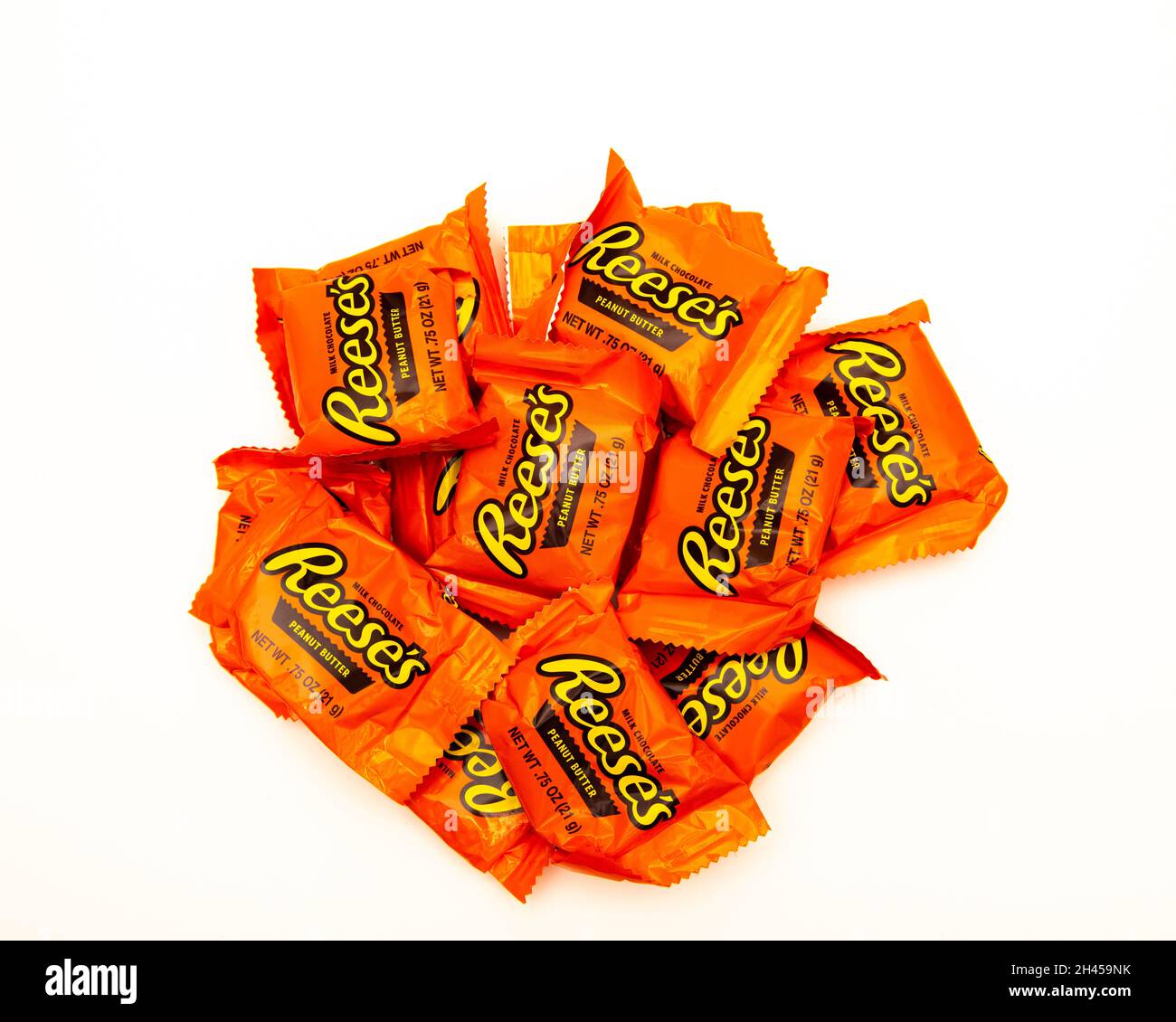 A pile of Reese's peanut butter cups in bright orange wrappers, made with milk chocolate, a tasty gluten free treat or snack. Stock Photo