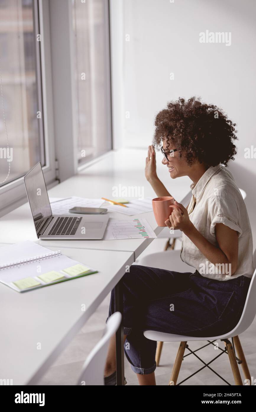 Happy African American lady waving hand during video conference Stock ...