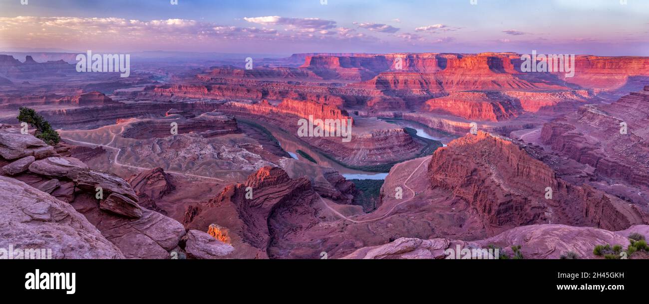 Smoky golden hour soft light hits the Colorado River Gooseneck, with smoke in the Colorado River Canyons in the distance at Dead Horse Point State Par Stock Photo