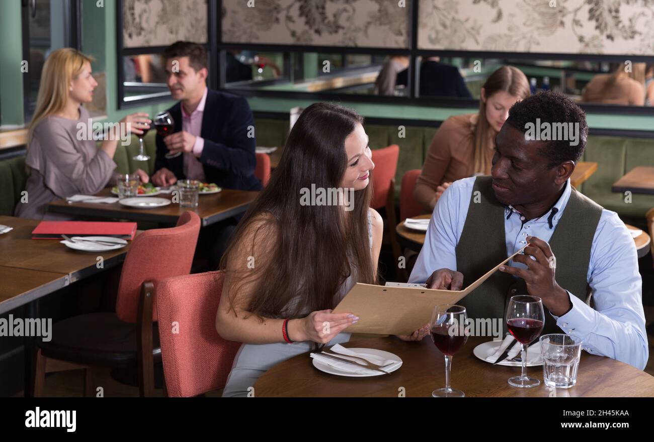 Happy couple discussing restaurant menu Stock Photo - Alamy