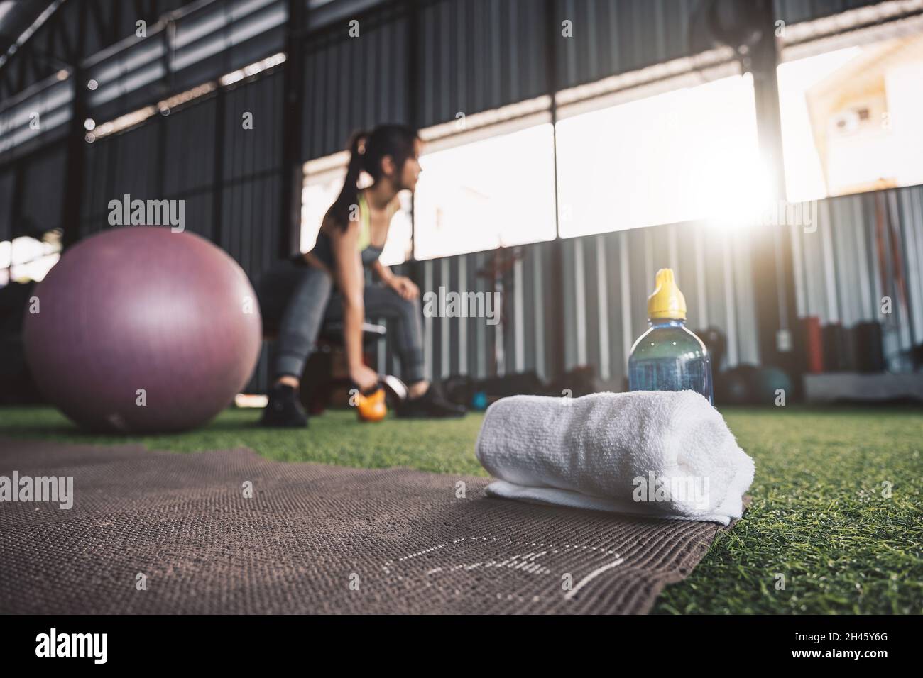 Selective focus towel and water bottle with woman workout fitness background. Stock Photo