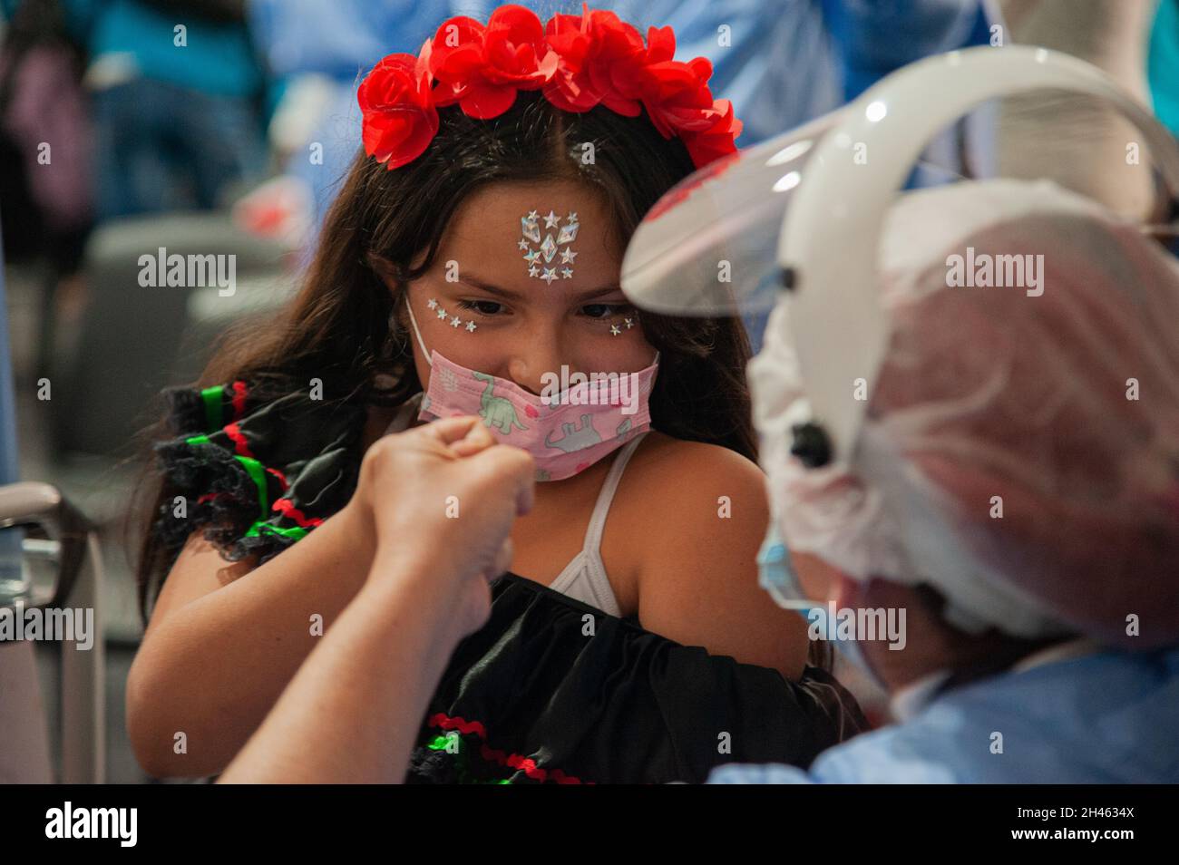 A girl dressed as a Mexican Catrina receives her first dose of the COVID-19 Vaccine as the Colombian government begins to vaccinate children between ages 3 to 11 against the Coronavirus disease (COVID-19) with the China's SINOVAC vaccine, in Bogota, Colombia on October 31, 2021. Stock Photo