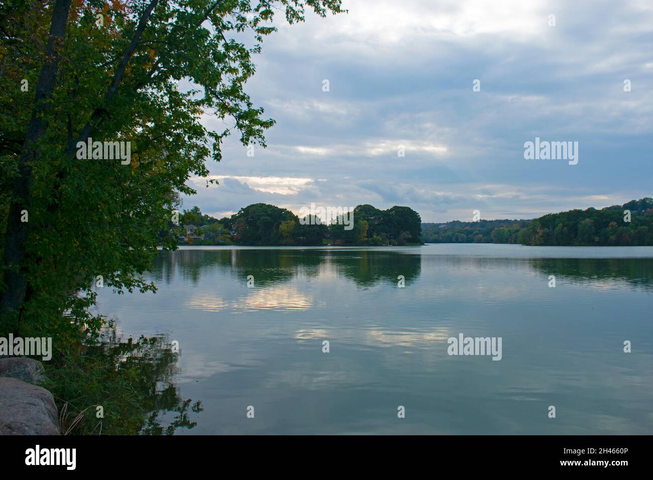 Clouds and trees reflecting on the still waters of Spy Pond, in Arlington, Massachusetts, on a cloudy autumn day -01 Stock Photo