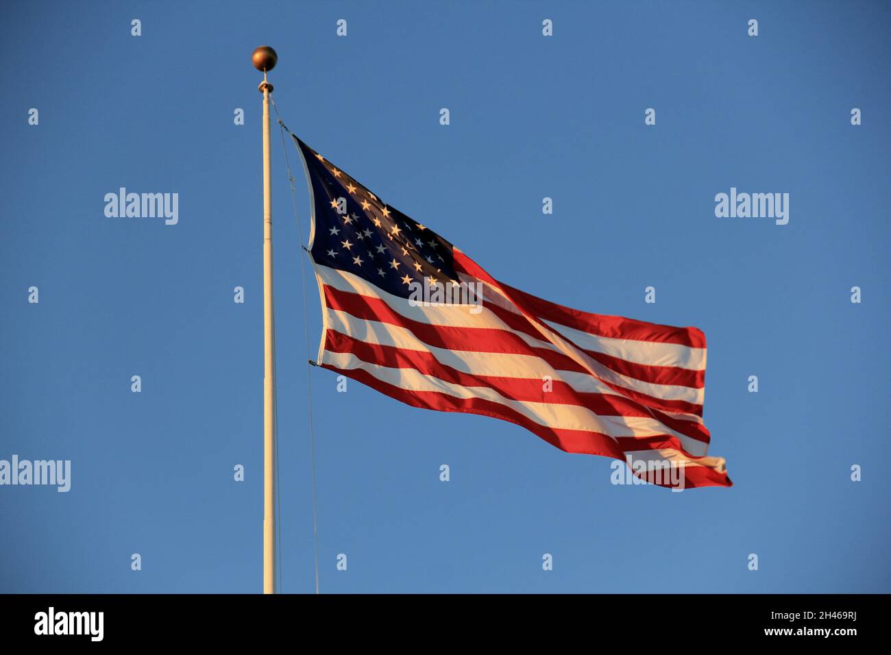 US Flag flying on a staff on blue sky background in sunset light Stock ...