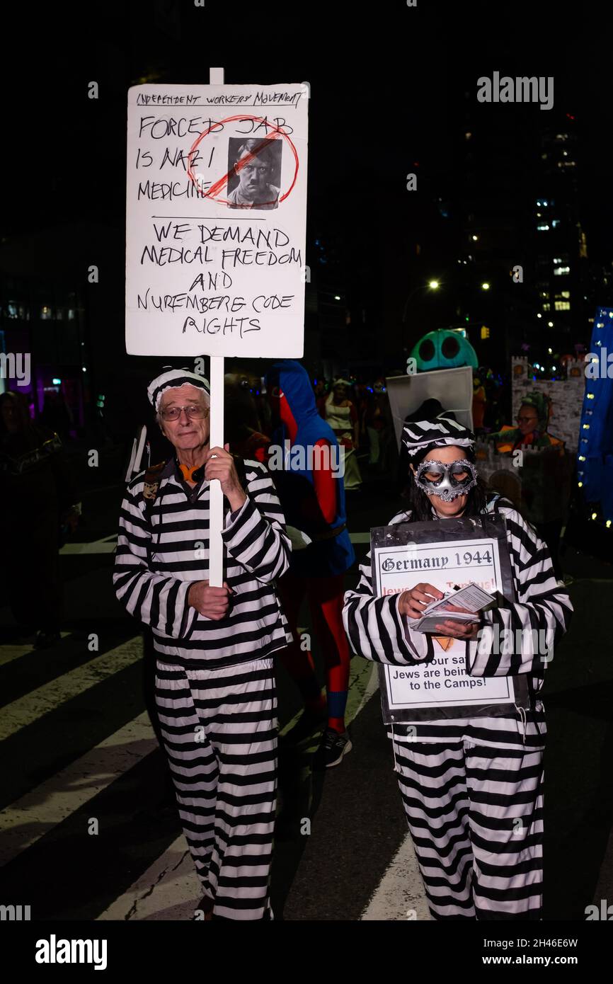 New York City, USA. 31st Oct, 2021. The annual Greenwich Village Halloween parade returned in 2021after a year's suspension because of COVID restrictions. Two people dressed in prison stripes carry signs comparing mandatory COVID vaccinations to war crimes. Credit: Ed Lefkowicz/Alamy Live News Stock Photo