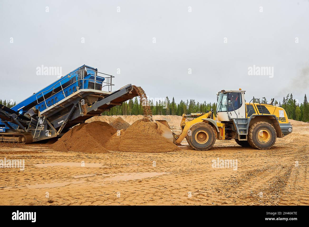 The front loader in the quarry collects a bucket of sand Stock Photo