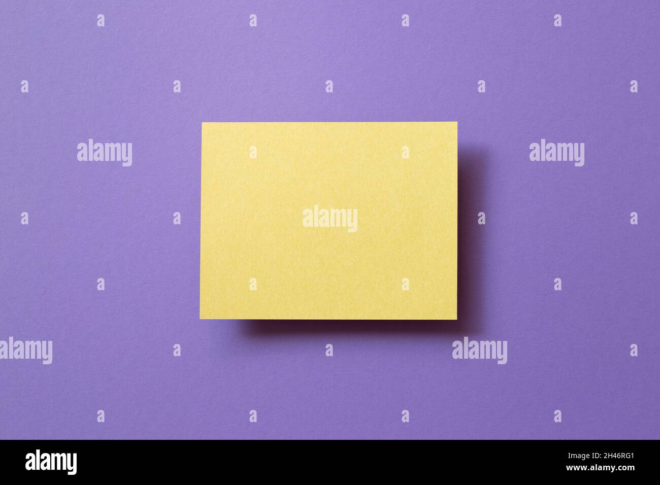 Blank yellow memo pad on purple background. top view, copy space Stock