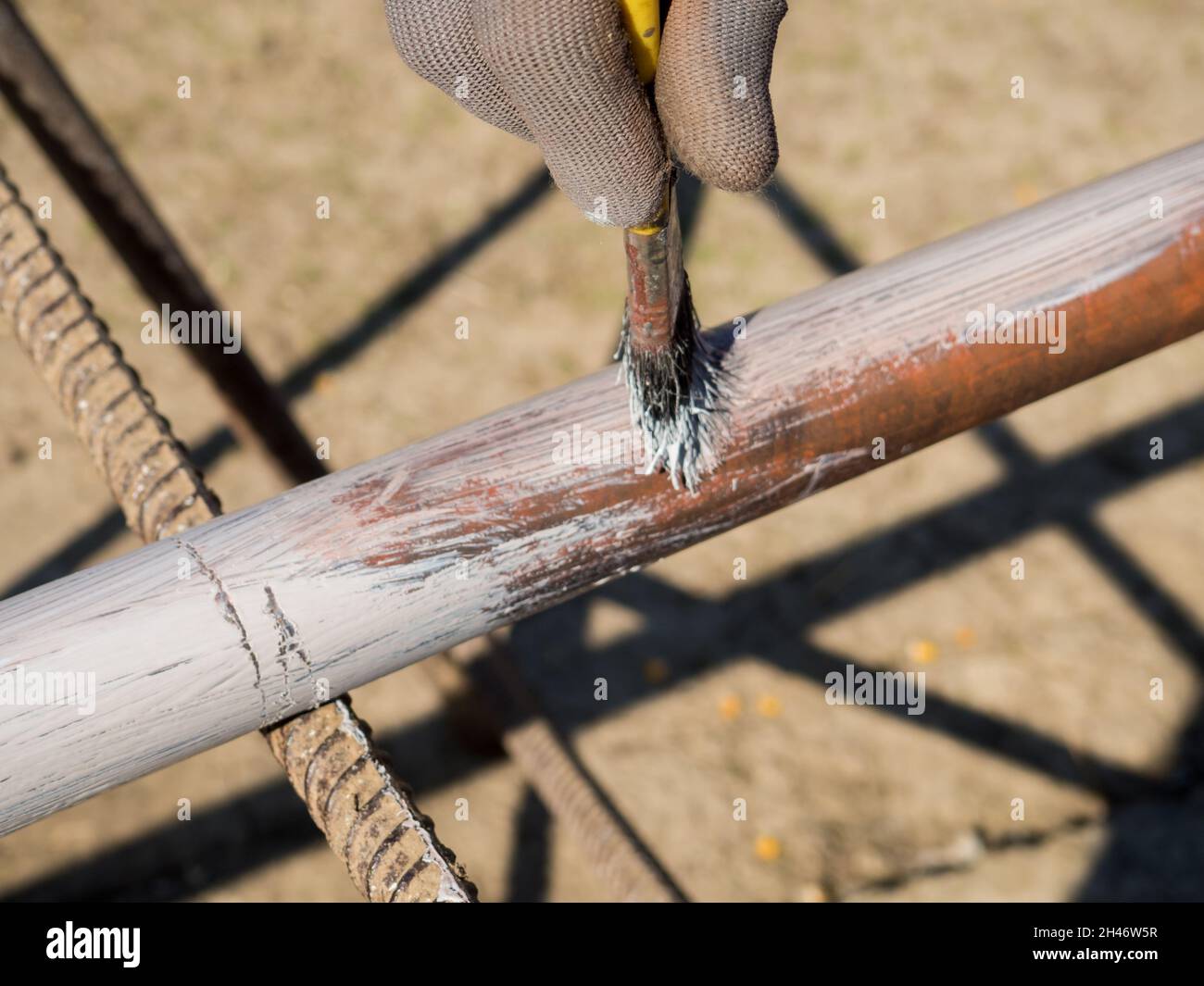 person primer painted metal pipe outdoors Stock Photo