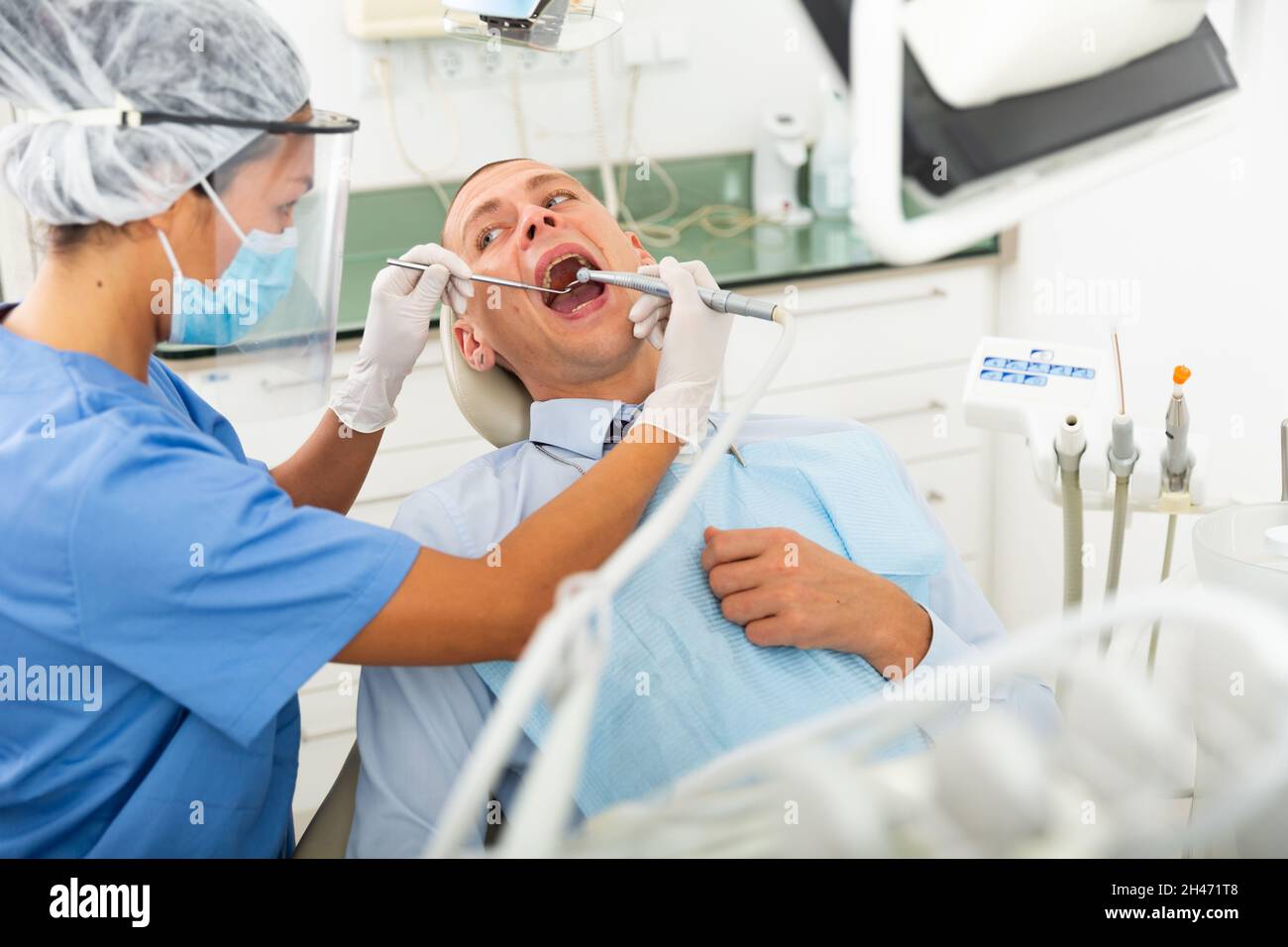 Female dentist drilling tooth to male patient Stock Photo Alamy