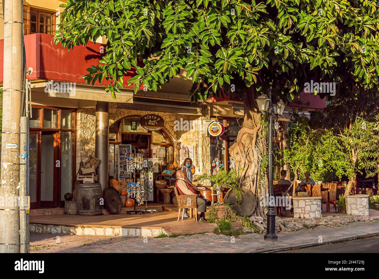 people sitting under a tree at an old café in the evening in Platanias, Crete, Greece, October 8, 2021 Stock Photo