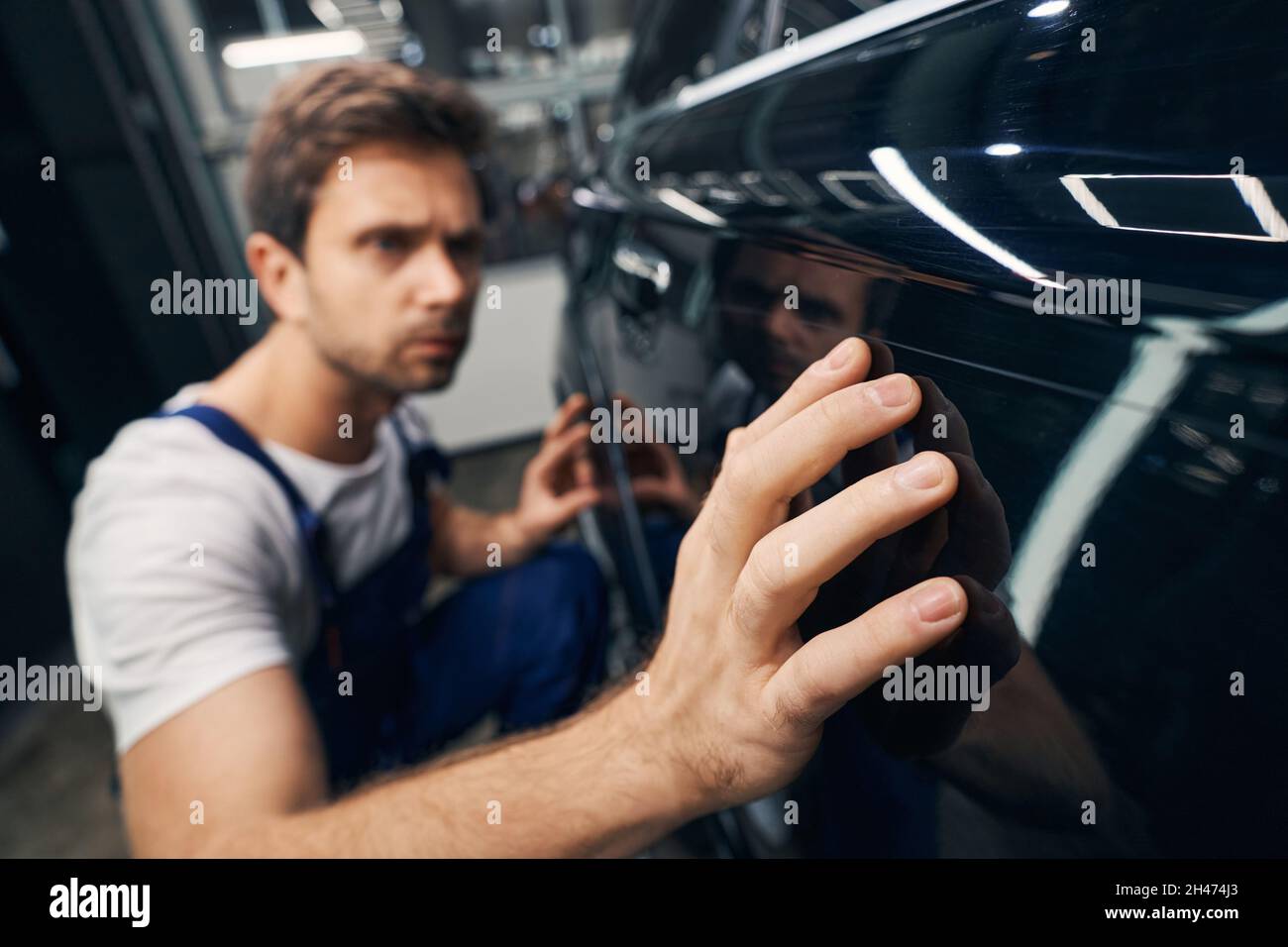 Hand of male repairman moving along automobile door Stock Photo