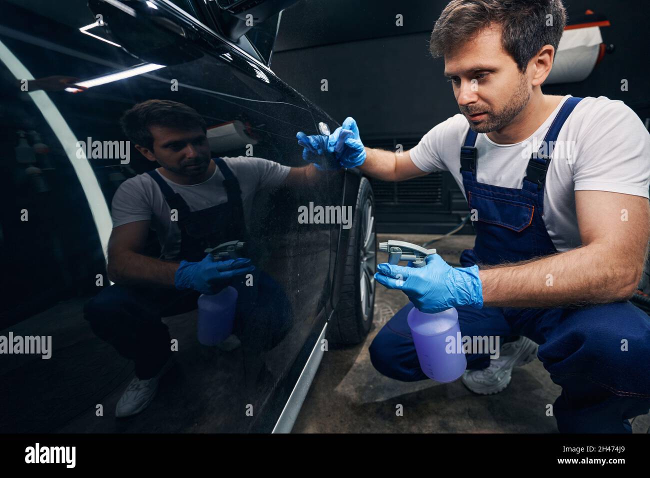 Auto repair shop worker spraying car with degreasing liquid Stock Photo