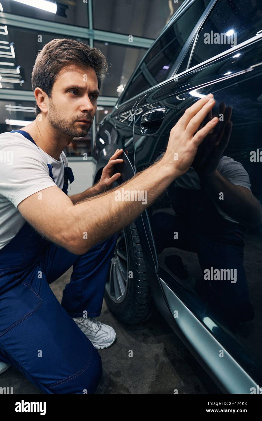 Man automotive technician looking for scratches on car Stock Photo