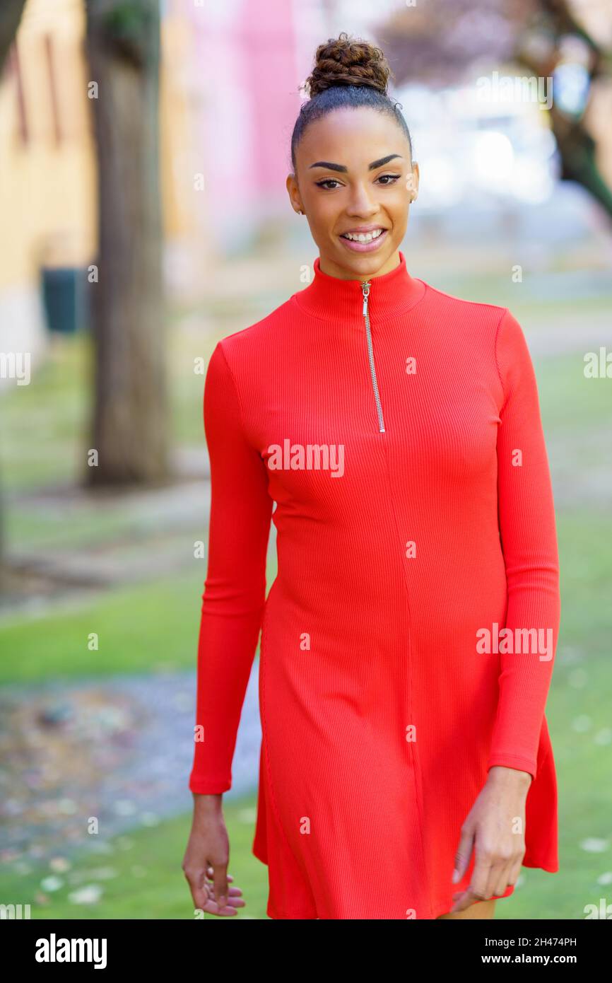 Smiling black woman in red dress walking down the street Stock Photo ...