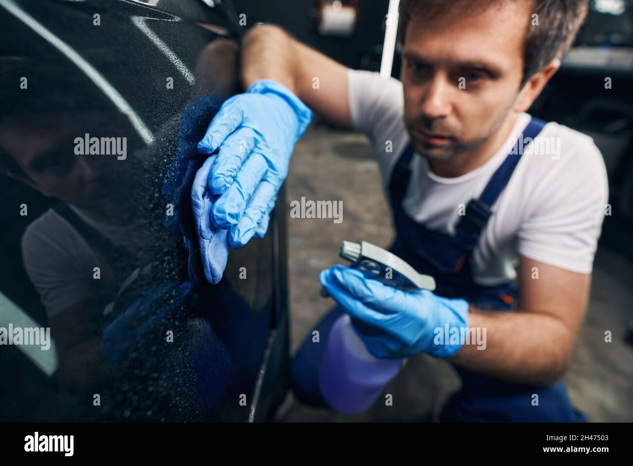 Worker of repair shop cleaning car with dustcloth Stock Photo