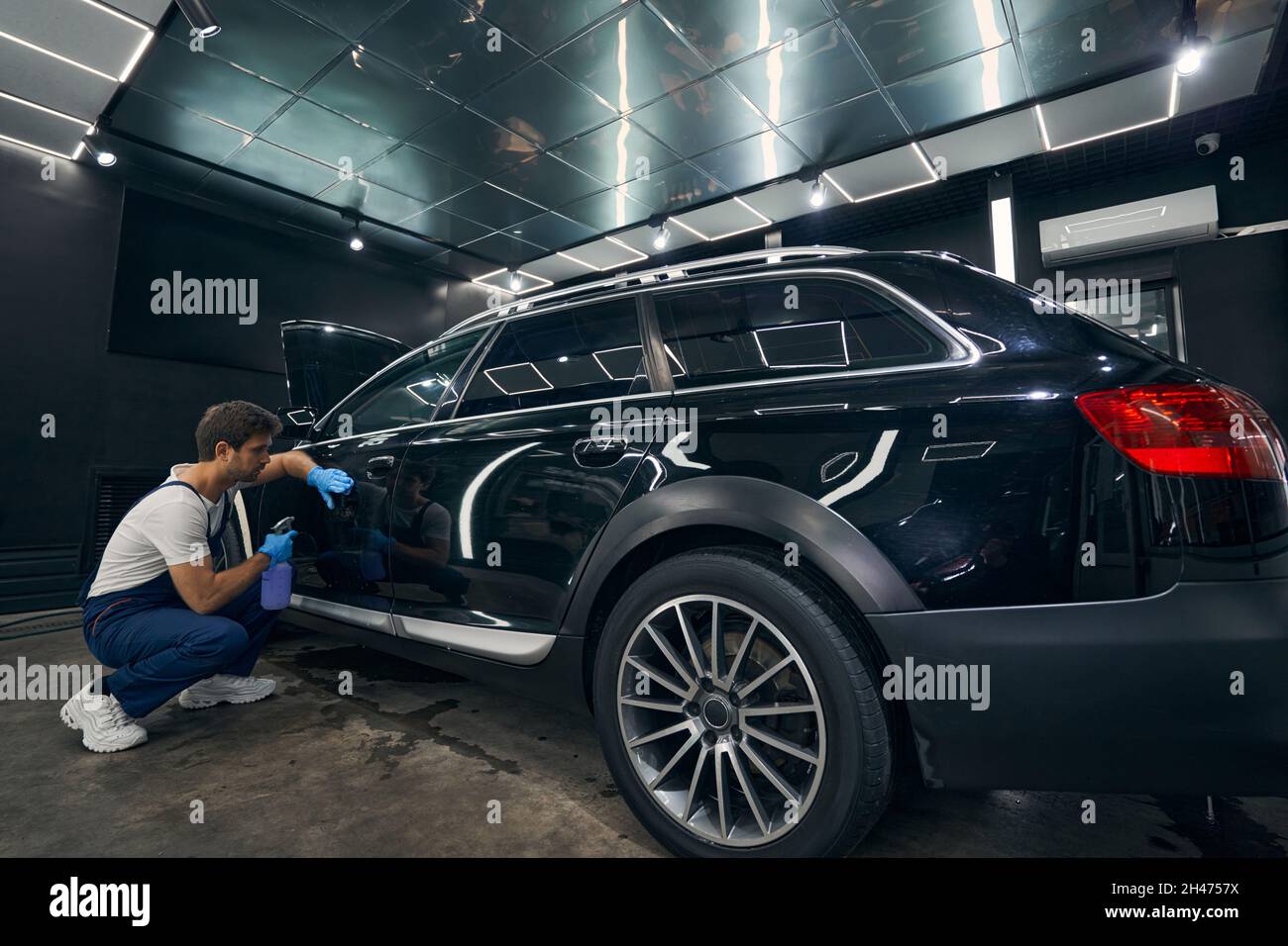 Black car undergoing cleaning procedure in automotive repair shop Stock Photo