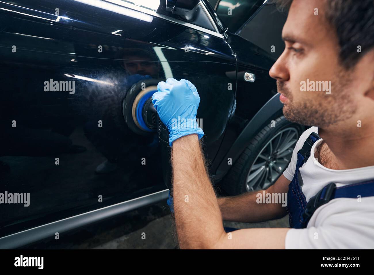 Car repair shop mechanic working away scratches with polisher Stock Photo