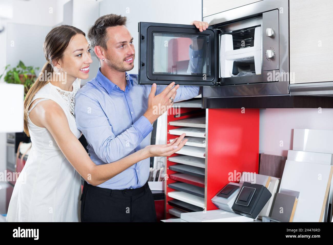 Happy young couple looking new microwave Stock Photo