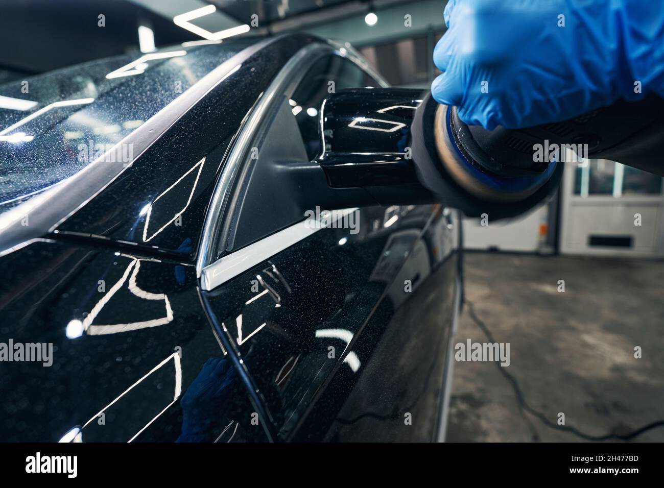 Worker of auto repair shop removing scratches from wing mirror Stock Photo