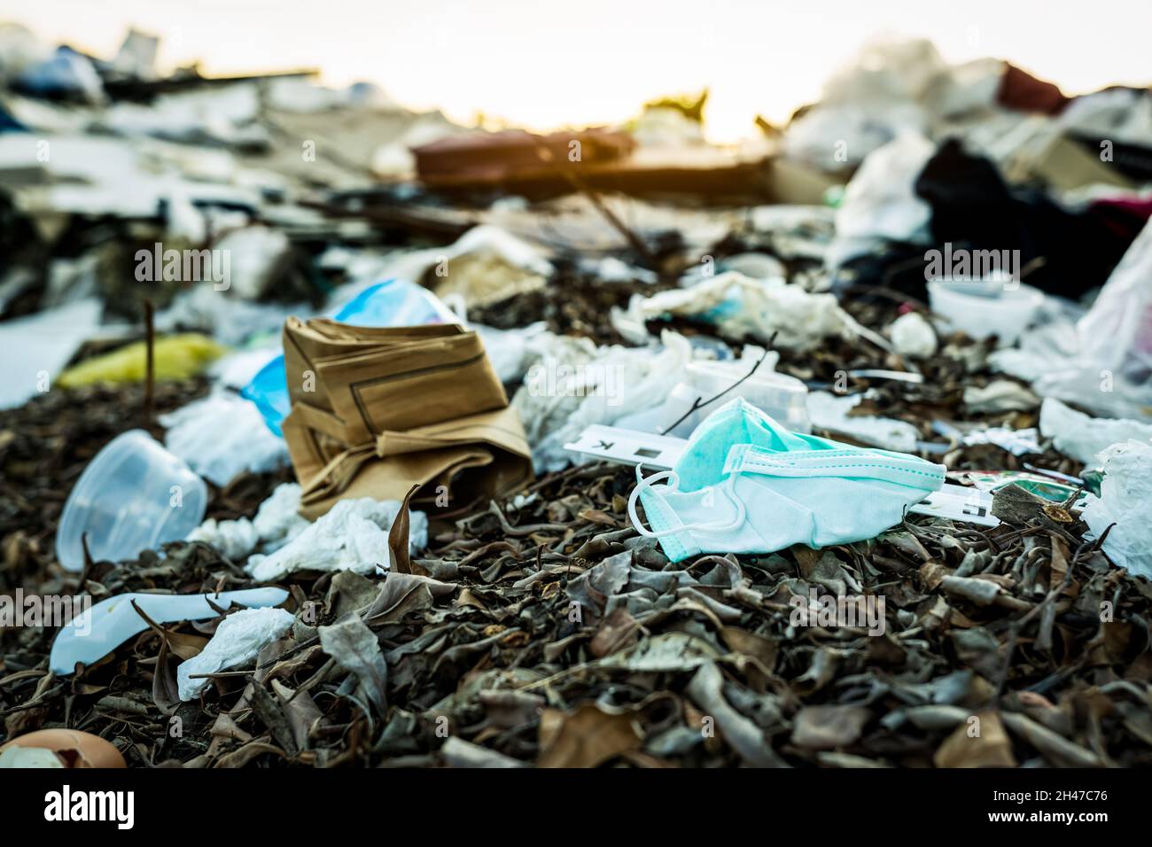 Used face mask discard in household garbage. Medical waste disposal with unhygienic management. Contaminated waste in community. Disposable earloop Stock Photo