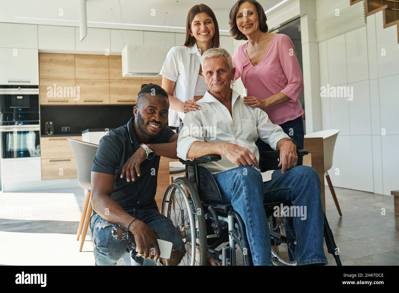 People supporting male with physical disability at home Stock Photo