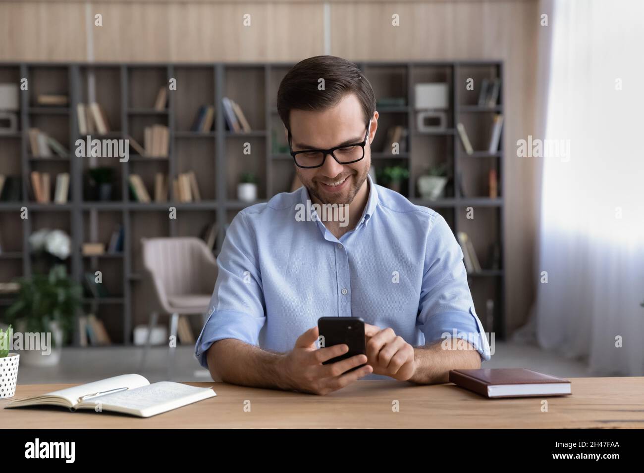 Smiling handsome young man using cellphone applications. Stock Photo