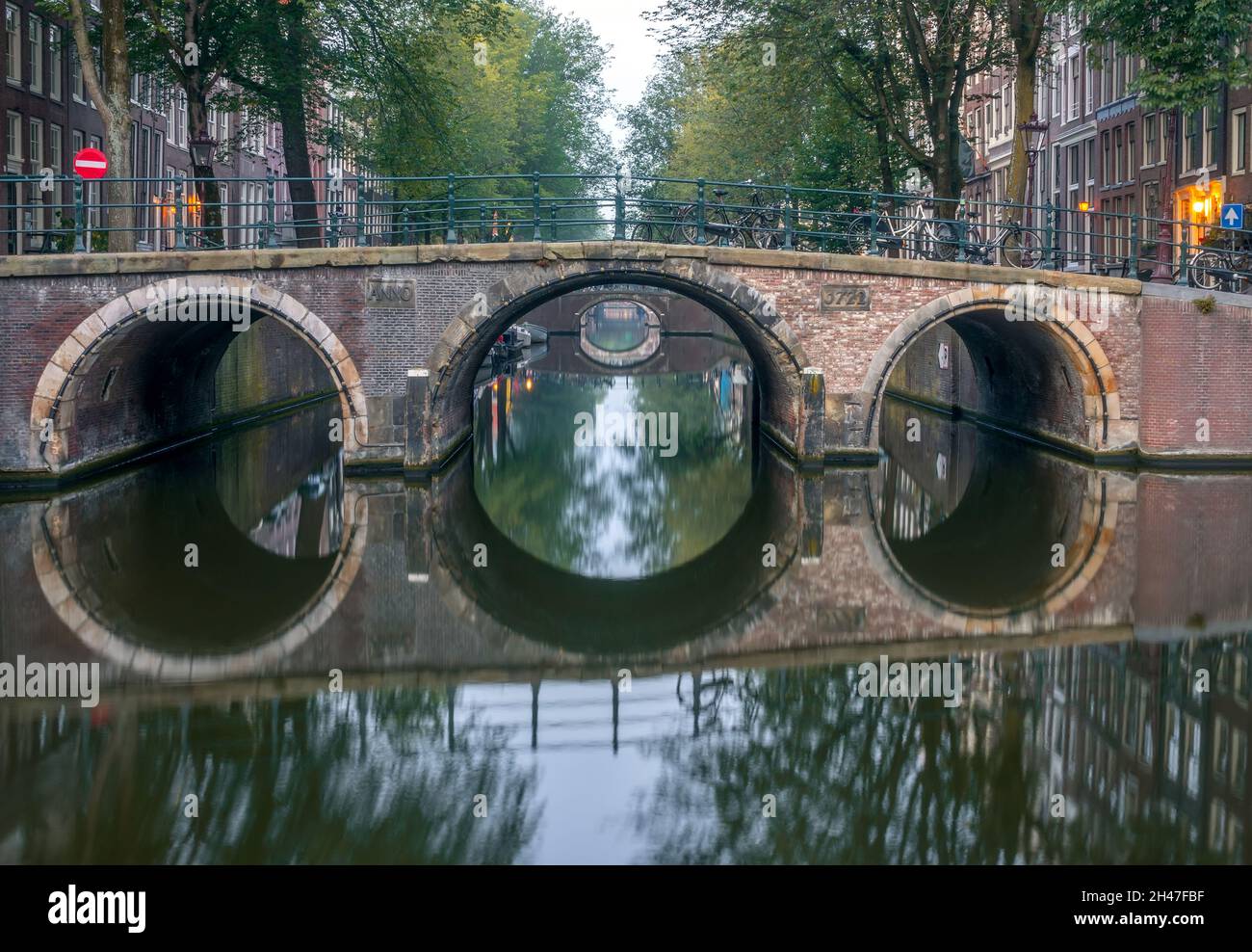 Netherlands. Morning on the Amsterdam Canal. Calm weather and a series of bridges with reflections Stock Photo