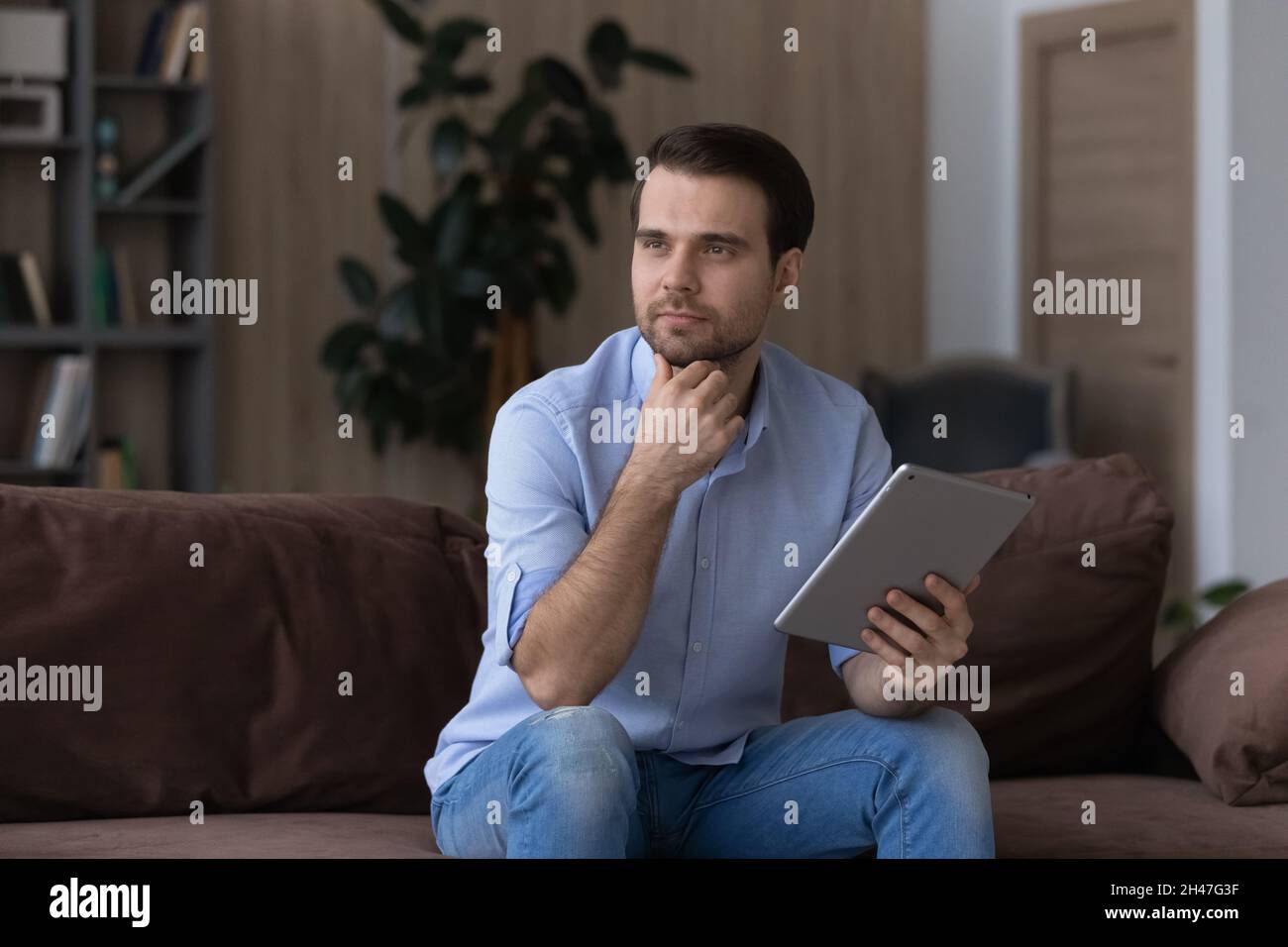 Thoughtful young handsome man using digital tablet. Stock Photo
