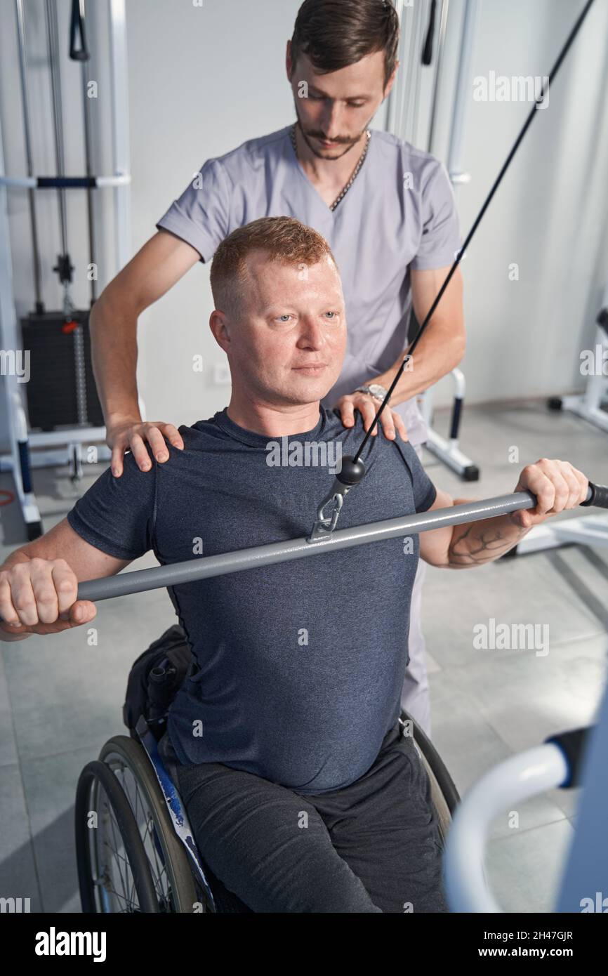 Physiotherapist help wheelchair man at recreation center. Back rehab Stock Photo Alamy