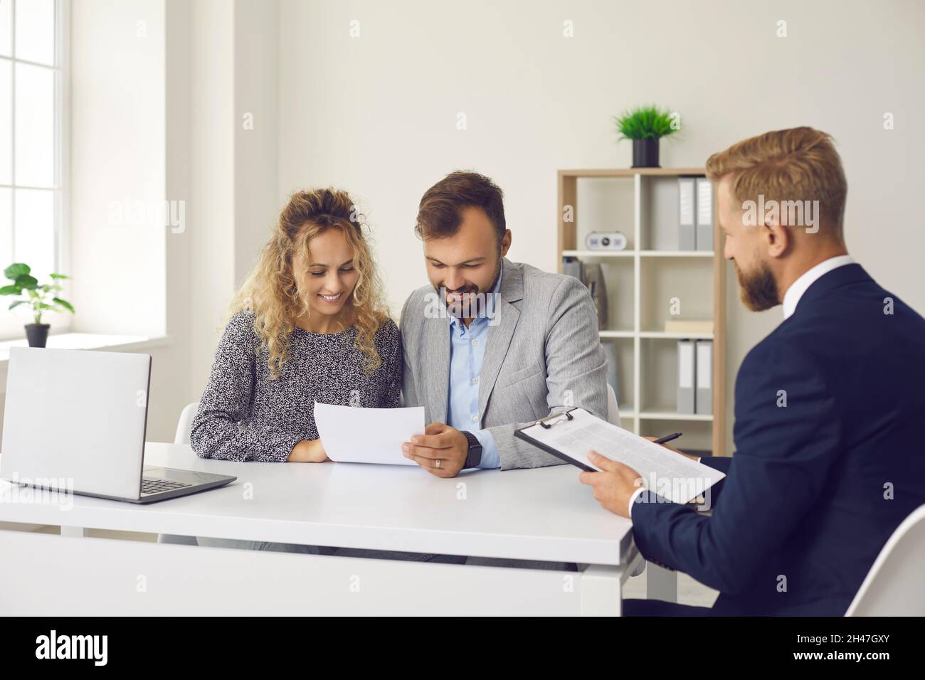 Happy young couple reading contract sitting at desk in real estate agent's office Stock Photo