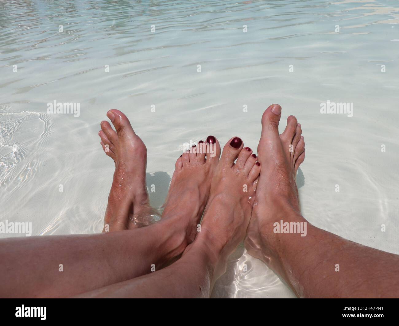 woman feet with polish on nails and her boy friend in swimming pool