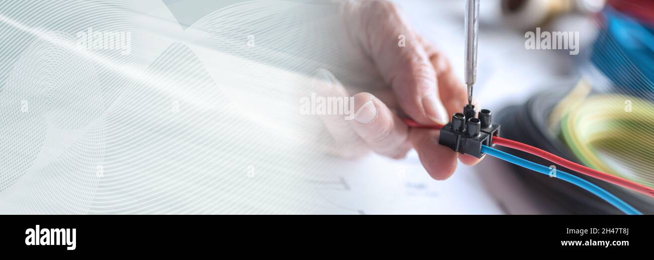 Electrician hands connecting wires in terminal block. panoramic banner Stock Photo