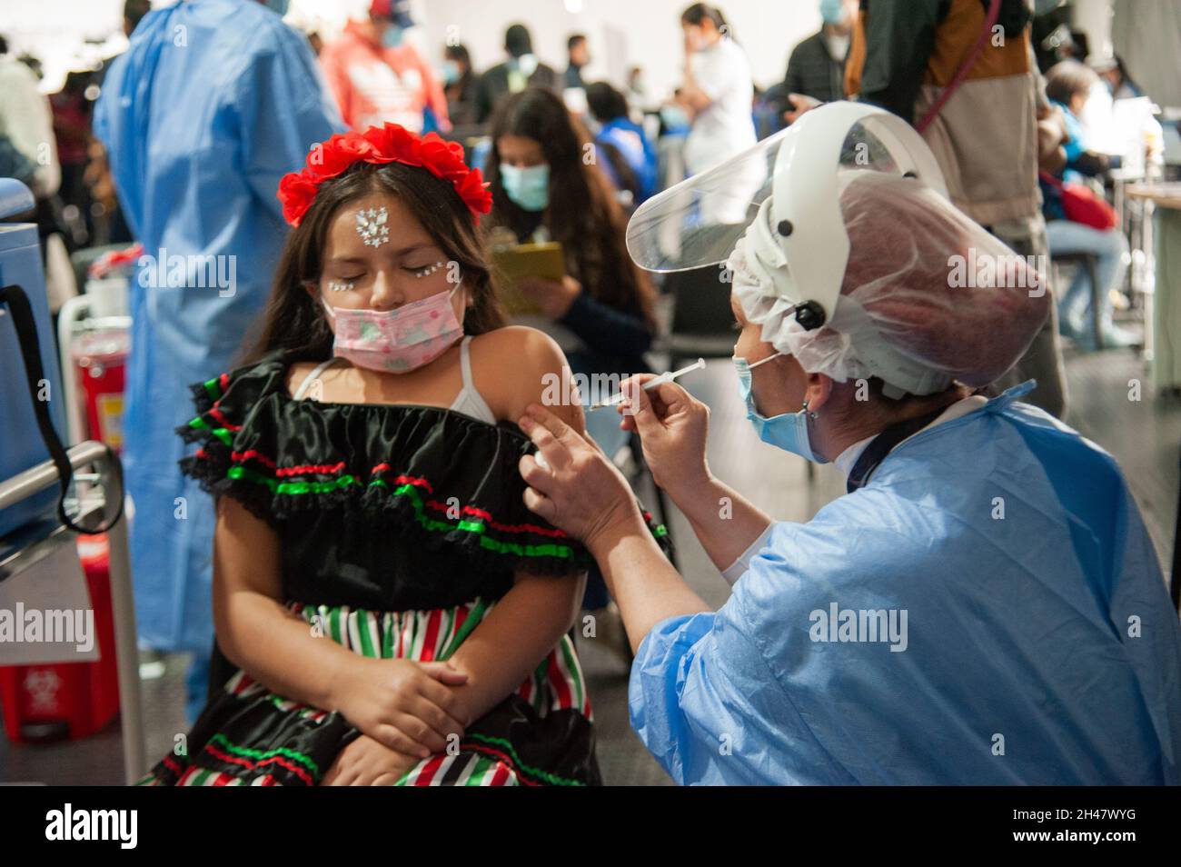 A girl dressed as a Mexican Catrina receives her first dose of the COVID-19 Vaccine as the Colombian government begins to vaccinate children between a Stock Photo