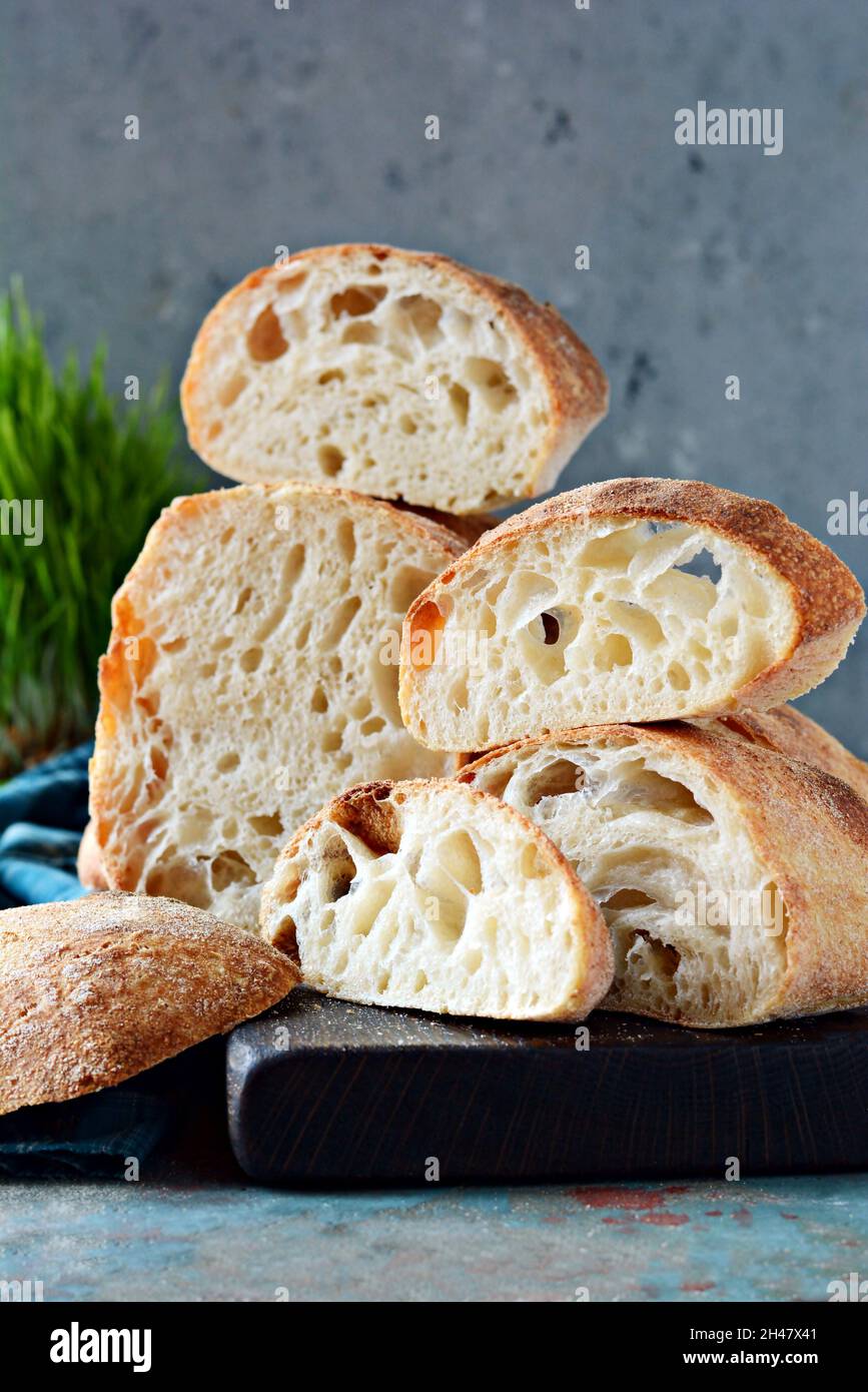 Fresh Italian ciabatta with crispy crust, moist crumb and large pores on a light blue background. Homemade sourdough bread (yeast-free). Food balance. Stock Photo