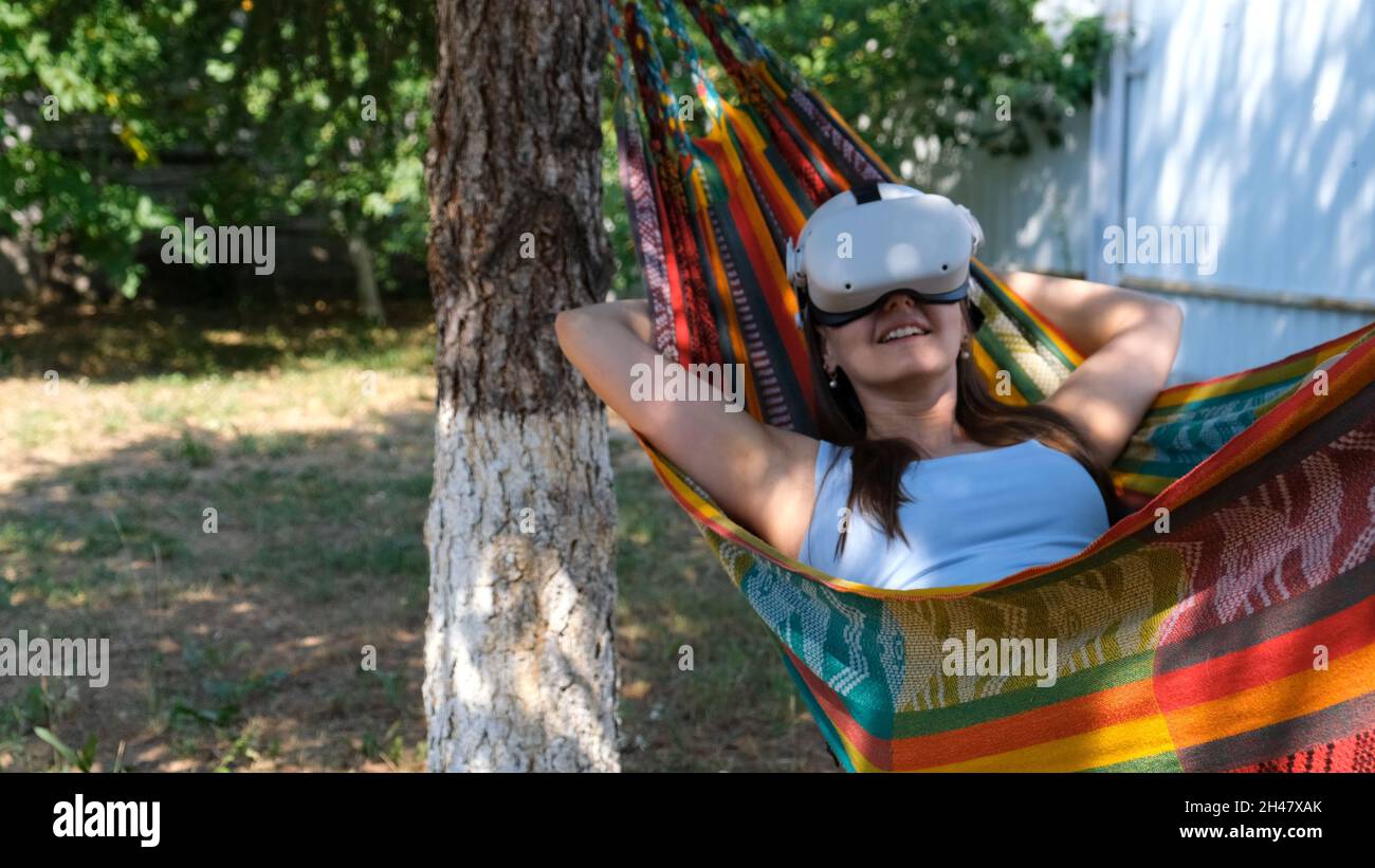 funny woman wearing virtual reality glasses rests in a hammock near a tree,  imagining a dream come true, an invented world. The concept of getting  Stock Photo - Alamy