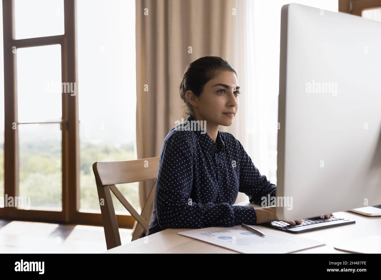 Concentrated millennial Indian businesswoman working online in office. Stock Photo