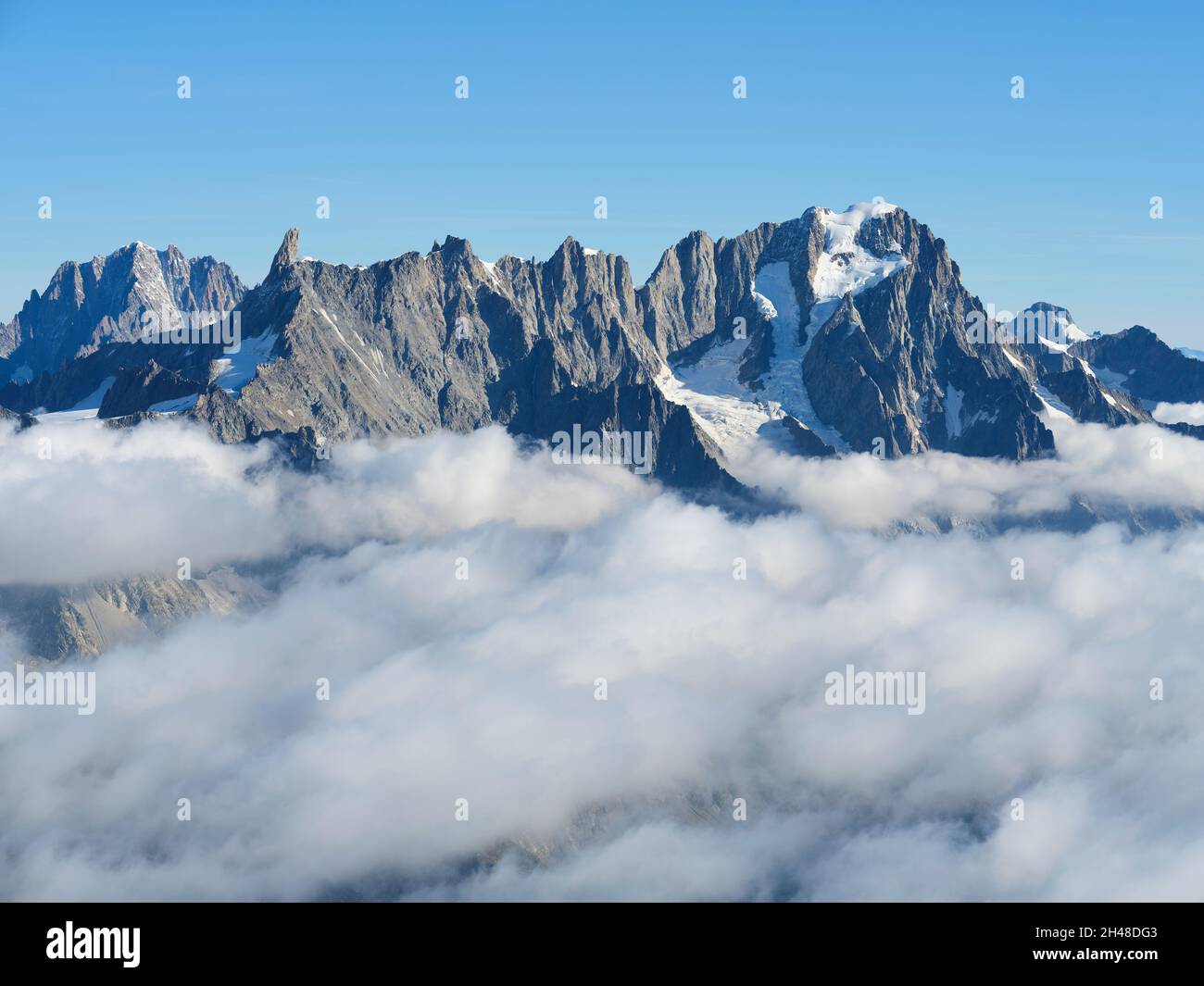 AERIAL VIEW. Southeastern face of Aiguille du Géant and the Grandes Jorasses above a sea of clouds. Val Ferret, Courmayeur, Aosta Valley, Italy. Stock Photo