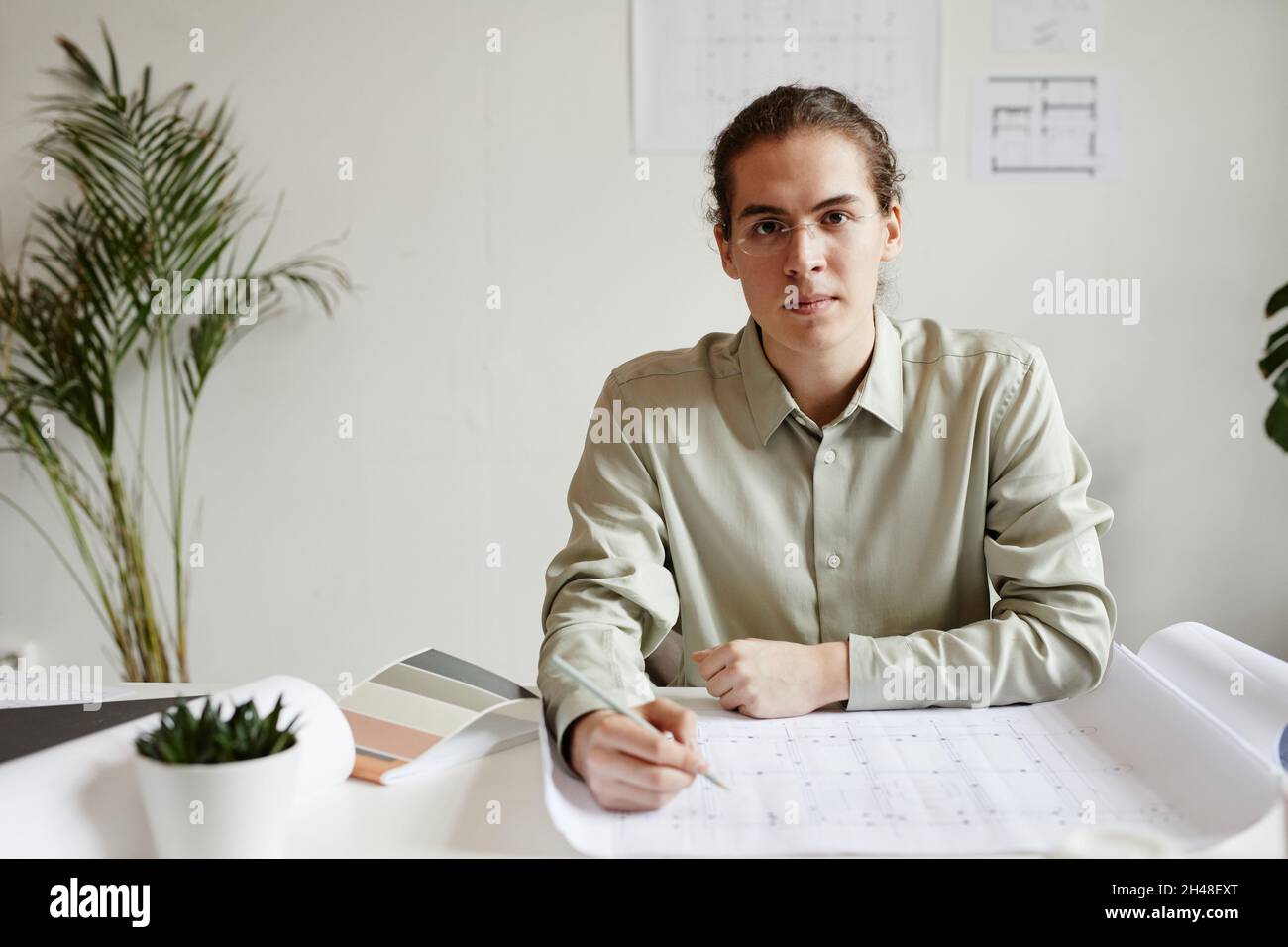 Minimal portrait of creative young man working at table in studio and looking at camera, copy space Stock Photo