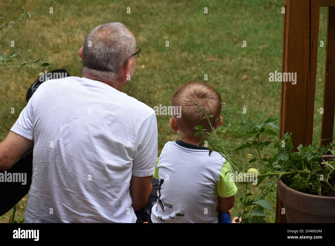 Grandfather and grandson sharing quality time during pandemic in backyard Stock Photo