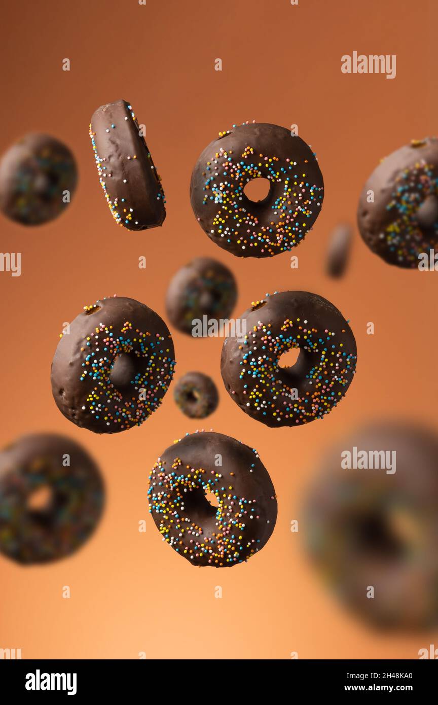 sweet chocolate donuts with multicolored sugar sprinkles on an orange ...