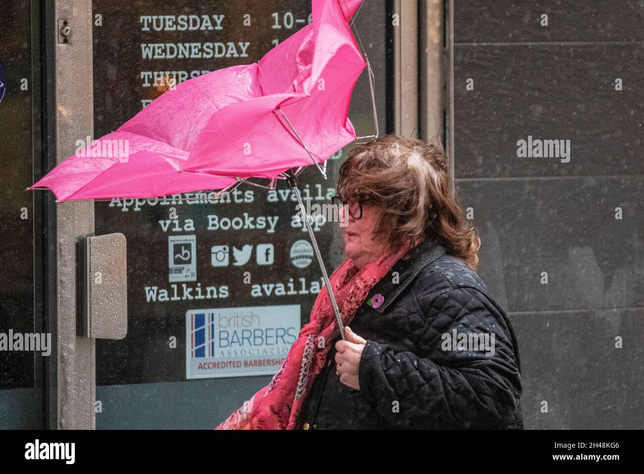 Strong winds and woman carrying inverted pink umbrella in Preston, Lancashire, UK. 1st November, 2021. UK Weather, broken umbrella, inverted, inside out, bent broken wind & rain.  Shops, shoppers shopping on a wet and windy day in Preston city centre.  Credit: MediaWorlImages/AlamyLiveNews Stock Photo