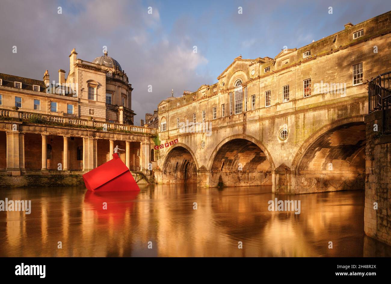 Pulteney Bridge, Bath, 1st November 2021.   At the break of dawn in Bath the sun illuminates Pulteney Bridge and the Cop 26 'The Sinking House' installation designed in collaboration with Stride Treglown, Format Engineers, Fifield Moss Carpentry and artist Anna Gillespie. It is also dawn at the United Nations Climate Change Conference where World leaders are set to address issues of an increased threat in the heightening global climate crisis. 'The Sinking House' represents a message of warning about and hope.  Credit: Casper Farrell/Alamy News Stock Photo